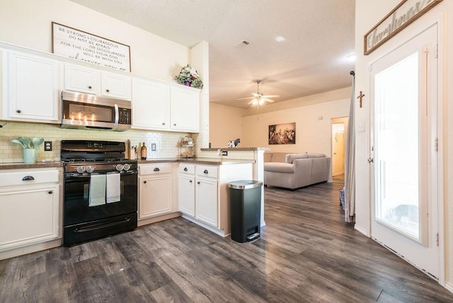 kitchen featuring black gas range oven, stainless steel microwave, open floor plan, a peninsula, and decorative backsplash