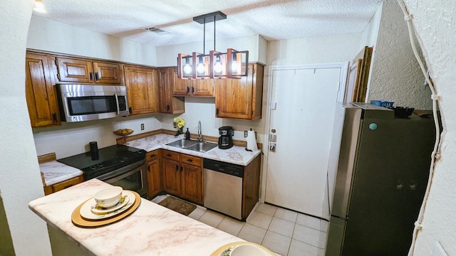 kitchen with appliances with stainless steel finishes, a textured ceiling, sink, and hanging light fixtures