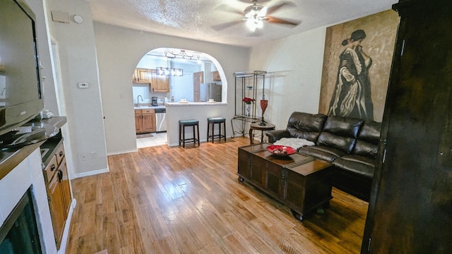 living room featuring ceiling fan, a textured ceiling, and light hardwood / wood-style flooring