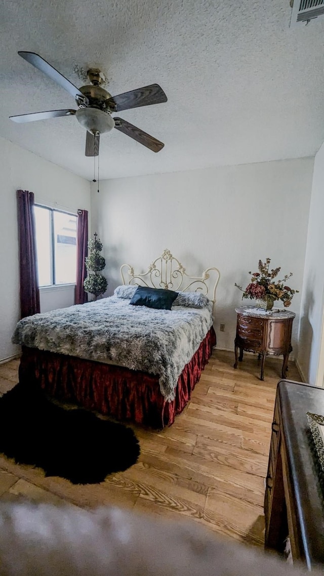 bedroom with a textured ceiling, hardwood / wood-style flooring, and ceiling fan