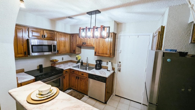 kitchen with hanging light fixtures, appliances with stainless steel finishes, a textured ceiling, light tile patterned flooring, and sink