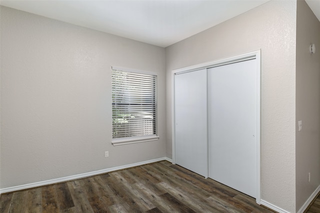 unfurnished bedroom with a closet and dark wood-type flooring