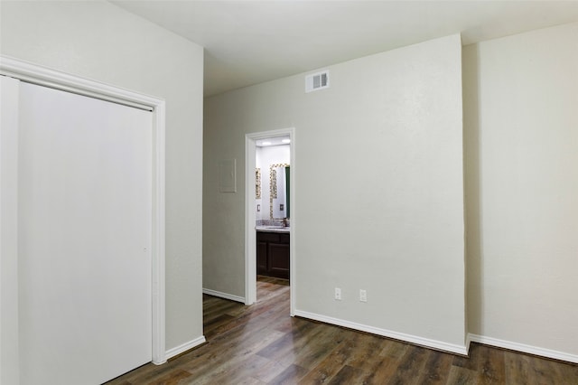 unfurnished bedroom with dark hardwood / wood-style floors and ensuite bath