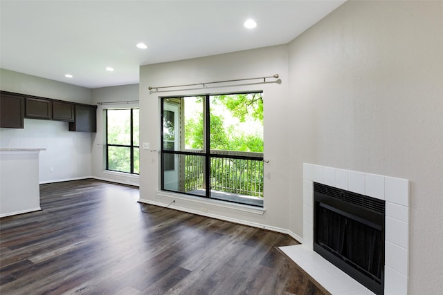 unfurnished living room featuring dark wood-type flooring and a tiled fireplace