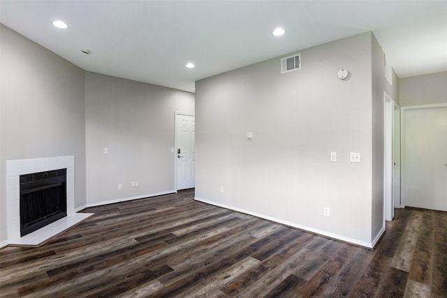 unfurnished living room with a tiled fireplace and dark hardwood / wood-style floors