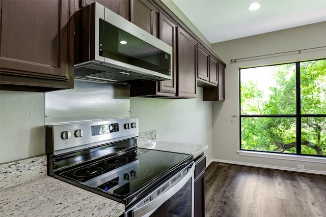 kitchen featuring a healthy amount of sunlight, light stone countertops, dark brown cabinetry, and appliances with stainless steel finishes