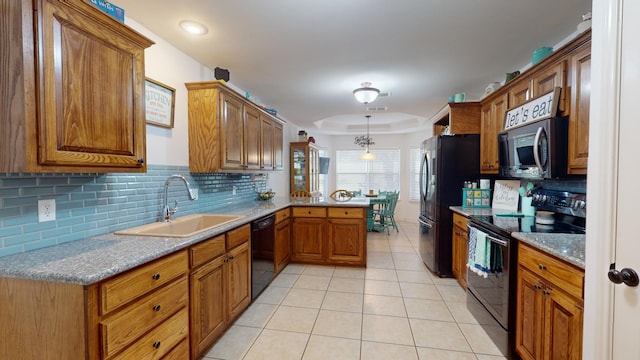 kitchen with black appliances, sink, kitchen peninsula, decorative backsplash, and a tray ceiling