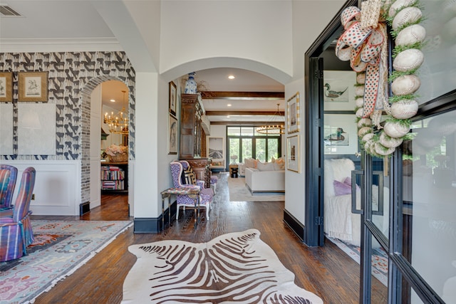 entryway with dark wood-type flooring, beamed ceiling, a notable chandelier, and crown molding