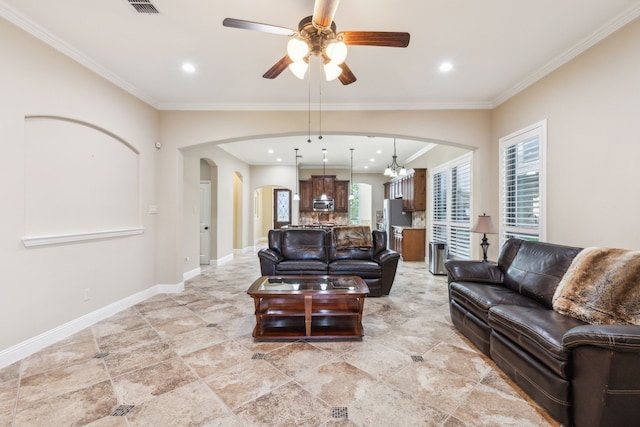 tiled living room with ceiling fan with notable chandelier and crown molding