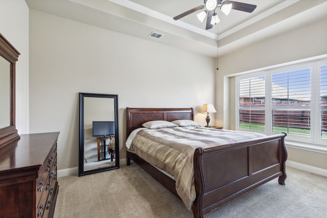 bedroom with light carpet, ceiling fan, a raised ceiling, and ornamental molding