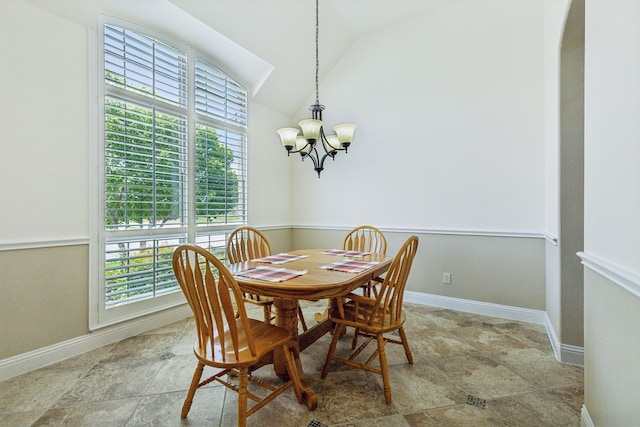 tiled dining room with a notable chandelier, vaulted ceiling, and plenty of natural light