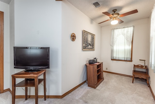 sitting room with light carpet, a textured ceiling, and ceiling fan