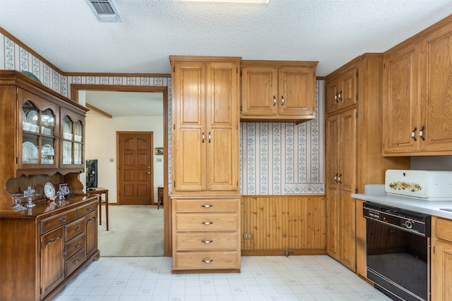 kitchen featuring light carpet, black dishwasher, and a textured ceiling