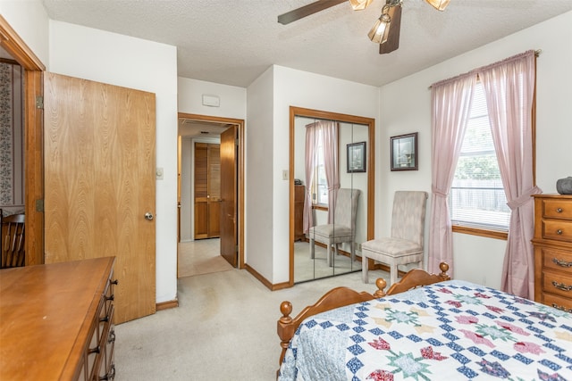 bedroom featuring a textured ceiling, light carpet, ceiling fan, and a closet