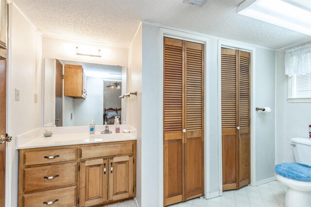 bathroom featuring tile patterned floors, toilet, vanity, and a textured ceiling