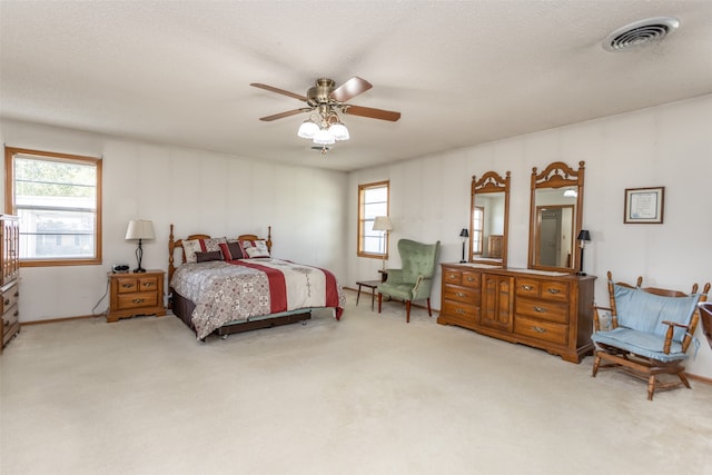 bedroom with light carpet, multiple windows, a textured ceiling, and ceiling fan