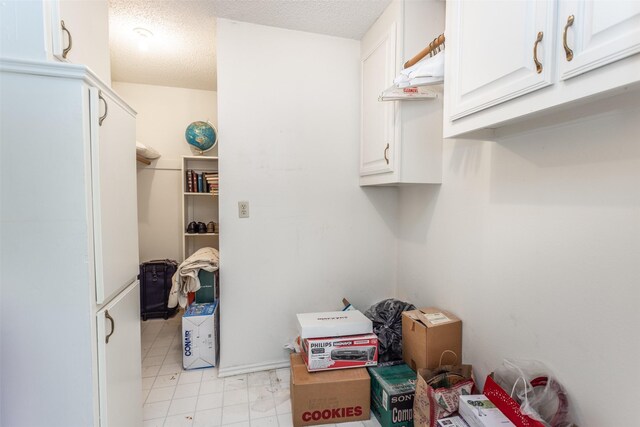 laundry area featuring a textured ceiling and light tile patterned floors