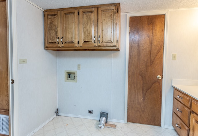 clothes washing area with cabinets, light tile patterned flooring, a textured ceiling, and washer hookup