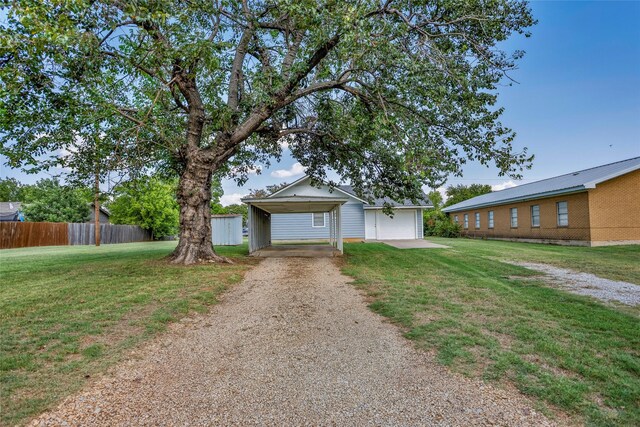 ranch-style home with a carport, a garage, an outbuilding, and a front lawn