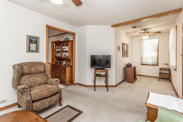 living room with a textured ceiling, ceiling fan, and light colored carpet