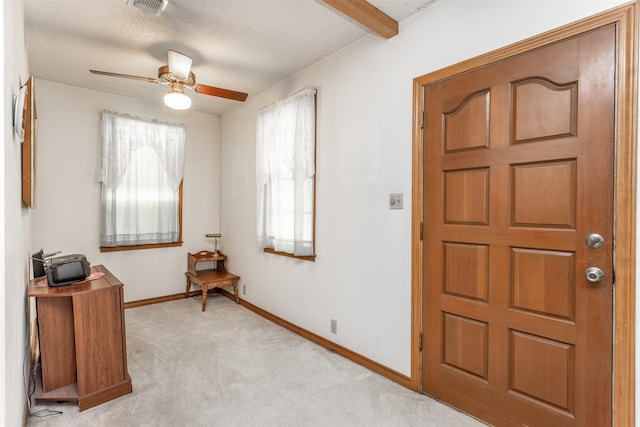 foyer featuring light carpet, ceiling fan, and a wealth of natural light