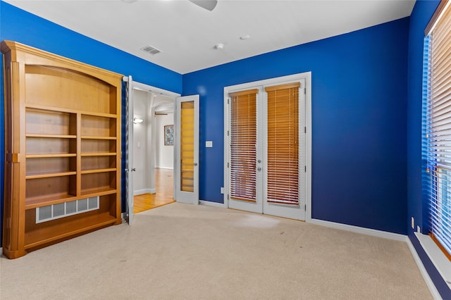 unfurnished bedroom with ceiling fan, french doors, and light colored carpet