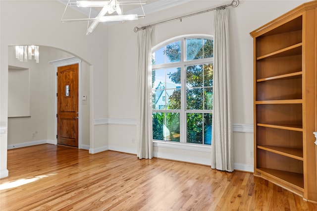 empty room featuring a notable chandelier and light wood-type flooring