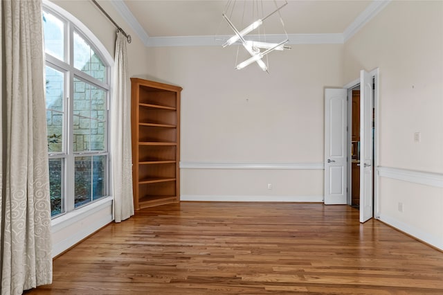 empty room featuring hardwood / wood-style flooring, an inviting chandelier, and ornamental molding