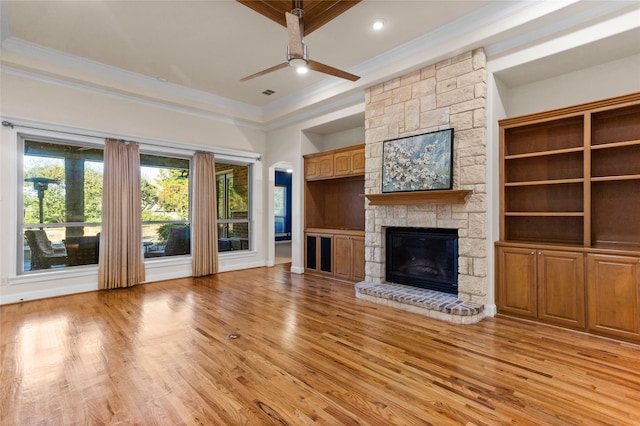 unfurnished living room featuring a fireplace, crown molding, light hardwood / wood-style flooring, and ceiling fan