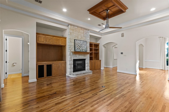 unfurnished living room featuring ceiling fan, a tray ceiling, hardwood / wood-style flooring, a fireplace, and ornamental molding