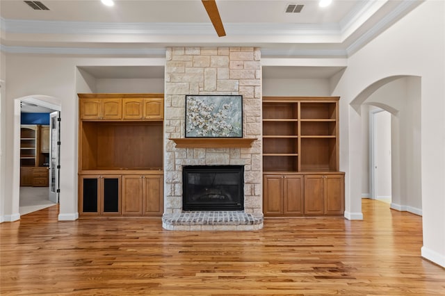 unfurnished living room featuring a stone fireplace, light hardwood / wood-style floors, and ornamental molding