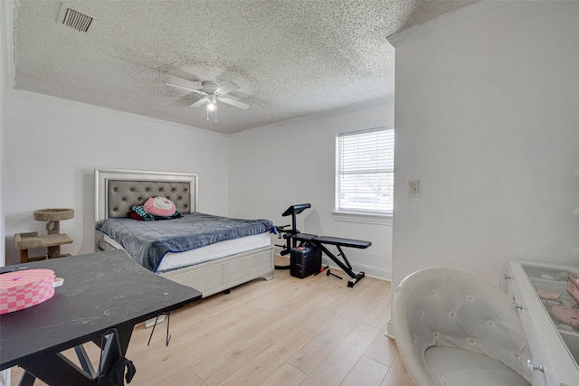 bedroom featuring ceiling fan, a textured ceiling, light hardwood / wood-style flooring, and ornamental molding