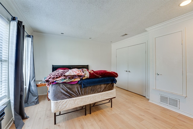 bedroom featuring crown molding, multiple windows, a textured ceiling, and light hardwood / wood-style flooring