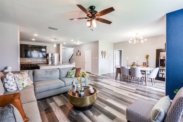 living room featuring ceiling fan with notable chandelier and light hardwood / wood-style floors