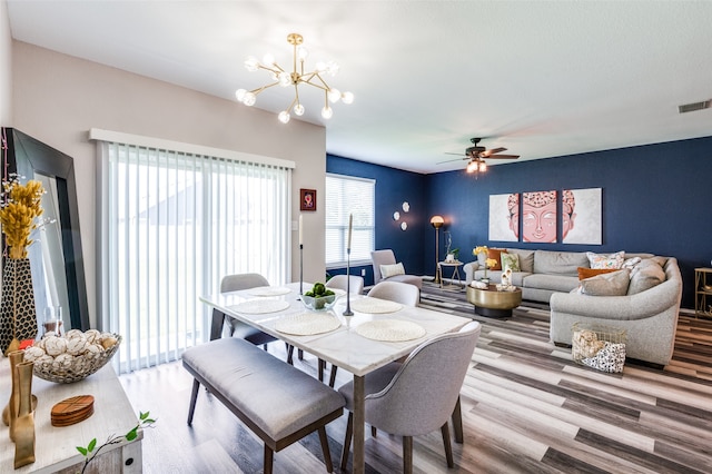 dining area with light hardwood / wood-style flooring and ceiling fan with notable chandelier