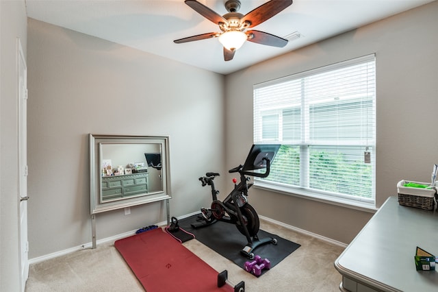 exercise area featuring light colored carpet, ceiling fan, and plenty of natural light