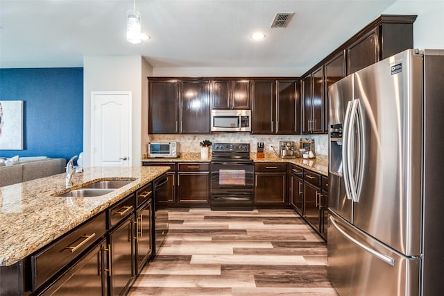 kitchen with dark brown cabinets, sink, light hardwood / wood-style floors, appliances with stainless steel finishes, and backsplash