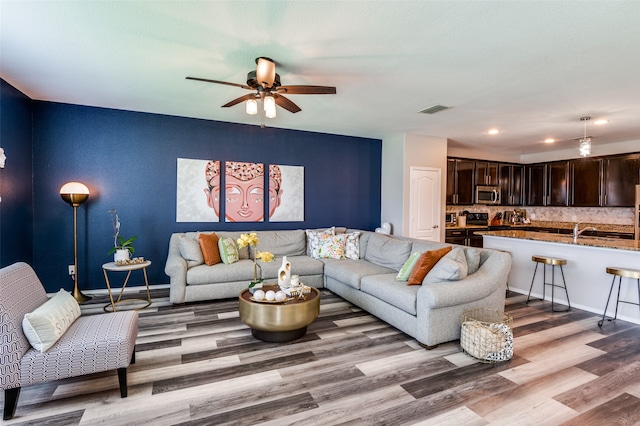 living room featuring light hardwood / wood-style flooring, sink, and ceiling fan