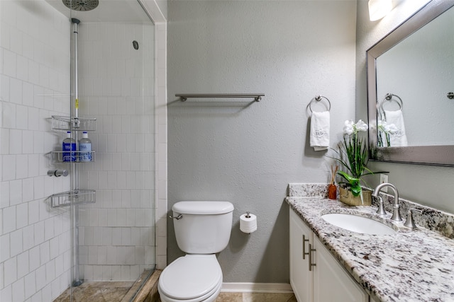 bathroom featuring vanity, a tile shower, and toilet