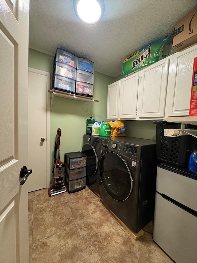 washroom featuring cabinets, washer and clothes dryer, and a textured ceiling