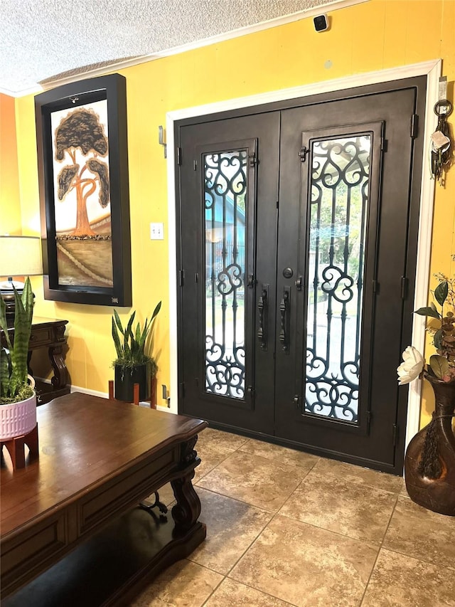 foyer entrance featuring crown molding, french doors, and a textured ceiling