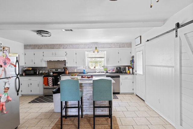 kitchen with appliances with stainless steel finishes, a barn door, and white cabinets