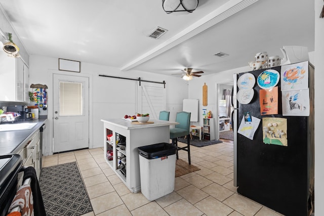 kitchen with white cabinets, black fridge, a barn door, and sink