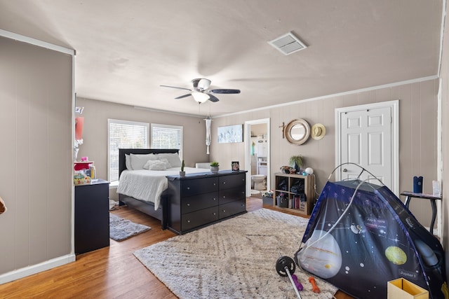 bedroom featuring hardwood / wood-style floors, ceiling fan, wood walls, and ornamental molding