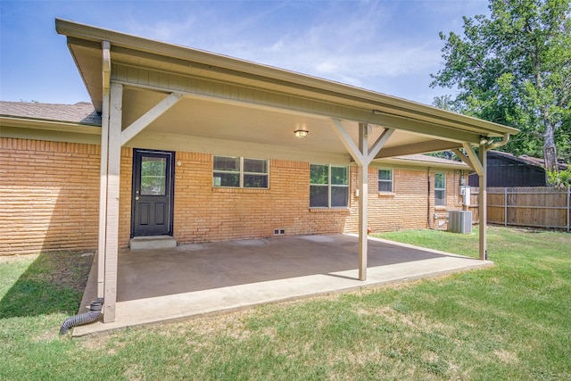 rear view of property featuring a lawn, a patio, fence, a carport, and brick siding