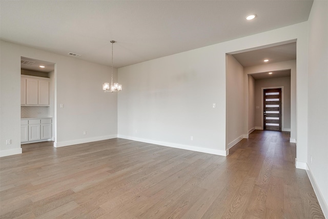 unfurnished room with light hardwood / wood-style floors and an inviting chandelier