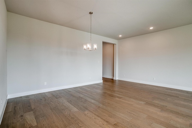 spare room featuring a notable chandelier and light wood-type flooring