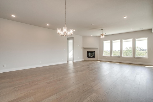 unfurnished living room with light wood-type flooring and ceiling fan with notable chandelier