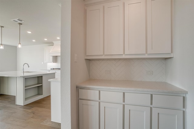 kitchen featuring white cabinetry, light hardwood / wood-style flooring, decorative backsplash, and decorative light fixtures