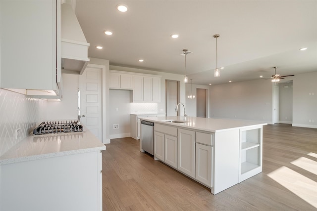 kitchen featuring appliances with stainless steel finishes, sink, white cabinetry, light hardwood / wood-style flooring, and a kitchen island with sink